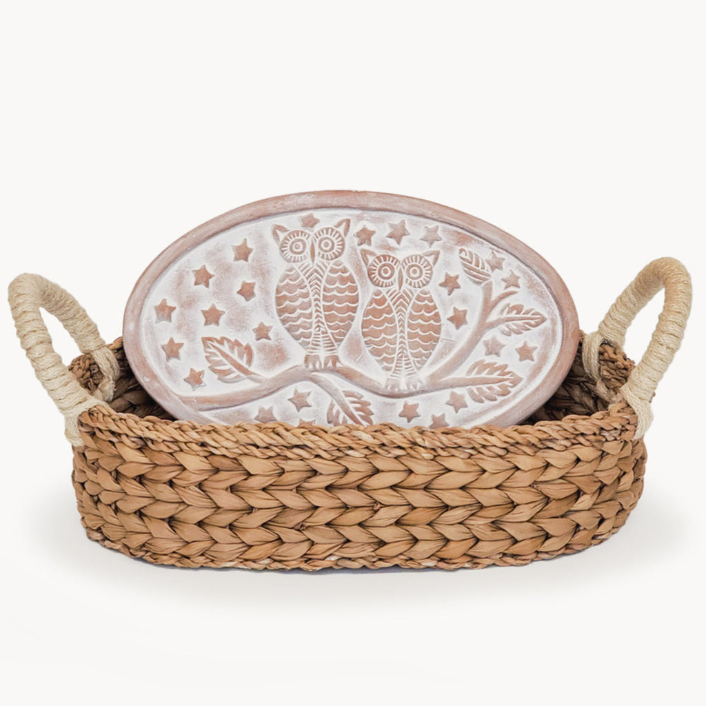 Decorative plate with owl design in a woven basket on a white background