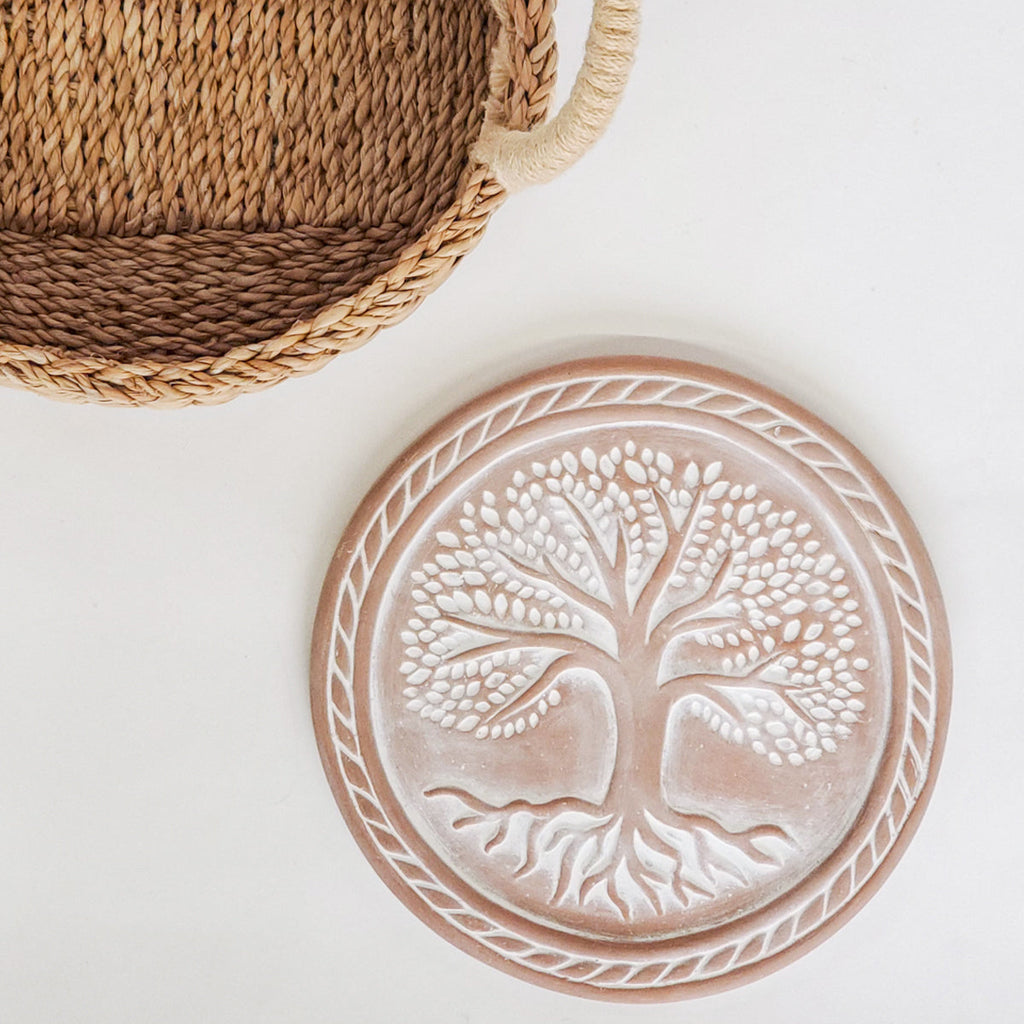 Woven basket and ceramic plate with tree design on a white background